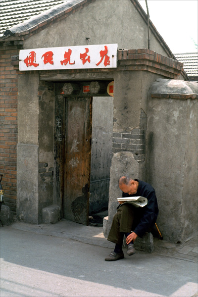 Man in hutong reading newspaper