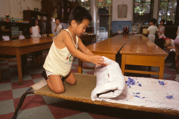 Child folds bedding at kindergarten