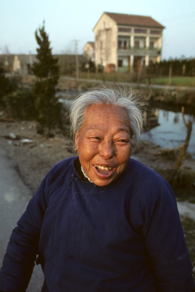Elderly woman with multi-storey rural house
