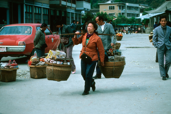 Woman carrying goods on shoulder pole, China