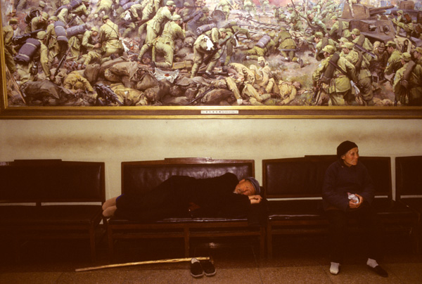 Man sleeps under painting of Chinese Revolution battle