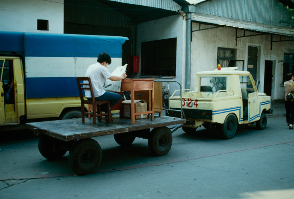 Man sitting at desk on trailer, Guangzhou, China