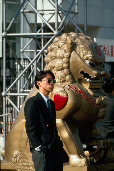 Man in suit with gold lion statue, Guangzhou, China
