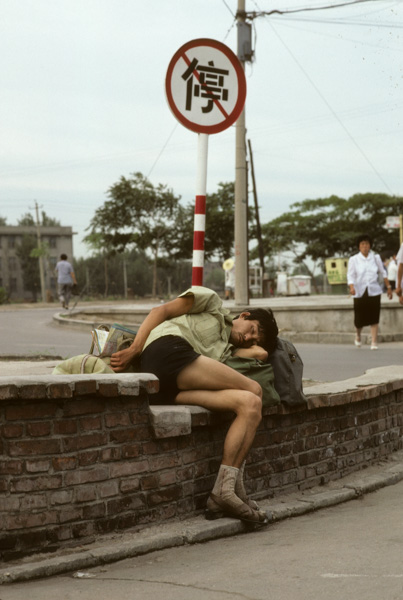 Young man sleeps by no parking sign