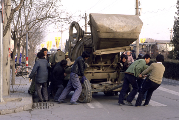 Workers push cement mixer