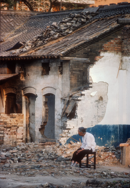 Woman sitting near demolished house