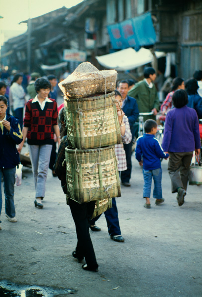 Woman carrying baskets, Xichang, China