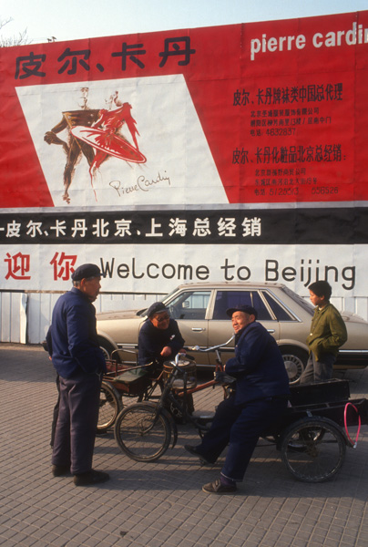 Men with bicycles and Pierre Cardin billboard