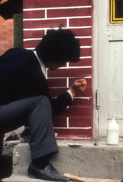 Man paints fake bricks on house