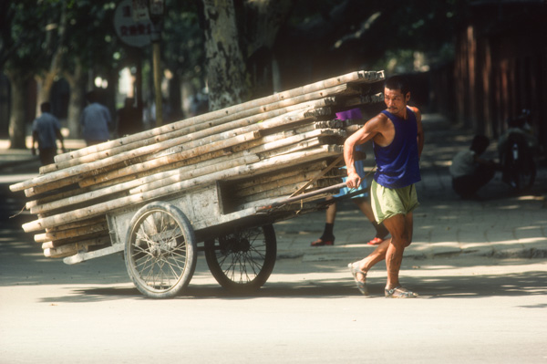 Man pulling load of wood, China