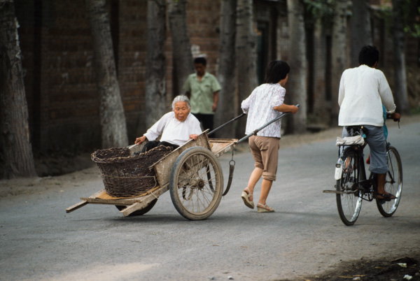 Woman pulls elderly woman in cart