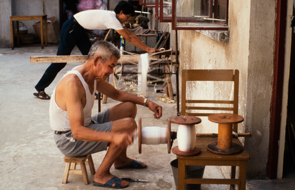 Man spinning thread onto spools, Beijing, China