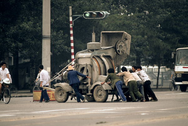 Workers push cement mixer